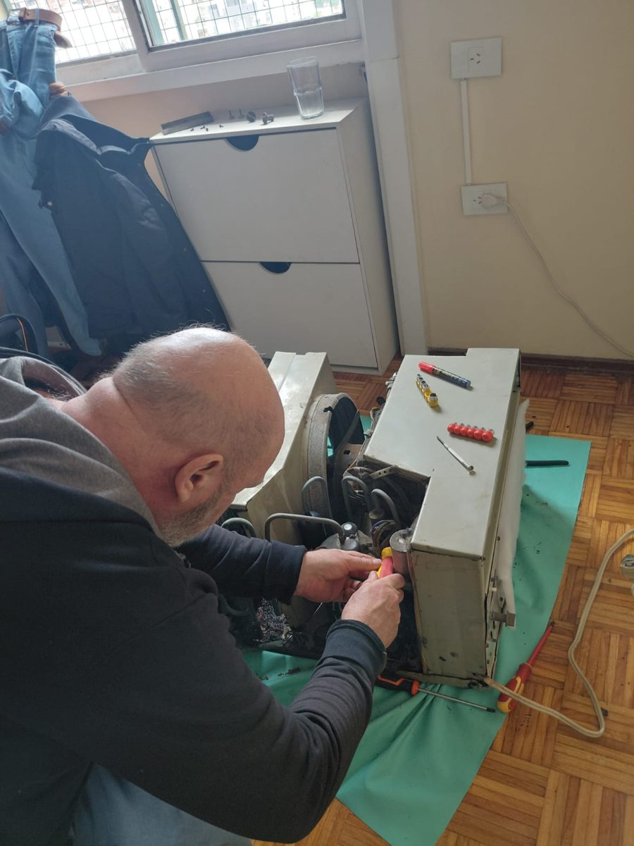 Técnico reparando un aire acondicionado de ventana a domicilio